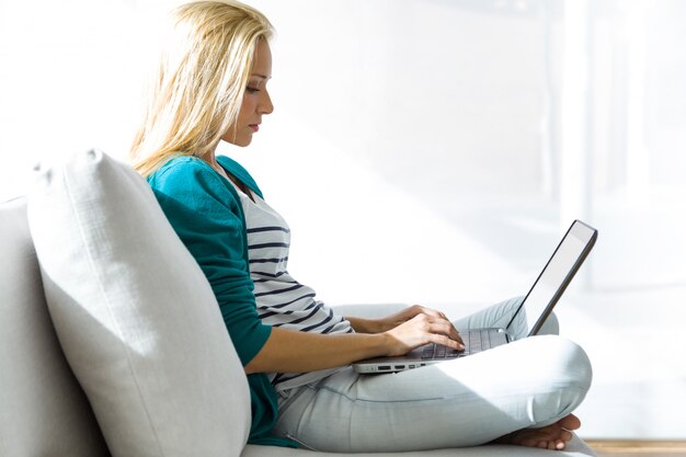 Mooie jonge vrouw die thuis met laptop werkt.