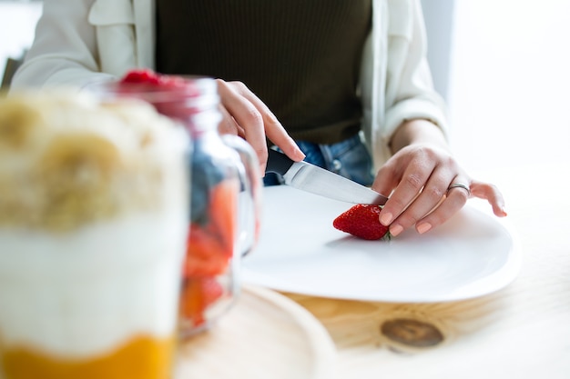 Mooie jonge vrouw die thuis ontbijt bereidt.