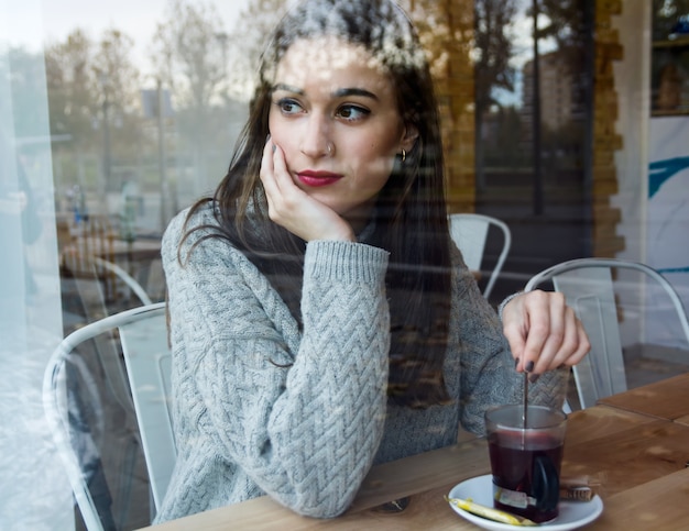 Mooie jonge vrouw drinken thee in een koffiewinkel.