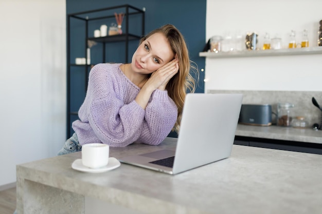 Mooie jonge vrouw glimlachend en thuis werken op laptop