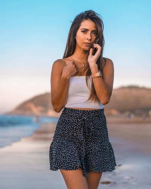 Mooie jonge vrouw in casual zomerkleding die zich voordeed tijdens het wandelen op het strand van Zarautz, Spanje