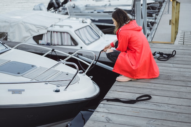 Mooie jonge vrouw in een rode mantel in de jachthaven. Stockholm, Zweden