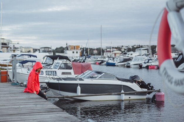 Mooie jonge vrouw in een rode mantel in de jachthaven. Stockholm, Zweden