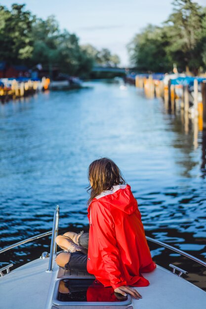 mooie jonge vrouw in een rode regenjas rijdt een prive-jacht. Stockholm, Zweden