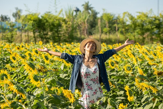 Mooie jonge vrouw in een veld met zonnebloemen in een witte jurk. reizen op het weekend-concept. portret van authentieke vrouw in strohoed. Buiten op het zonnebloemveld.