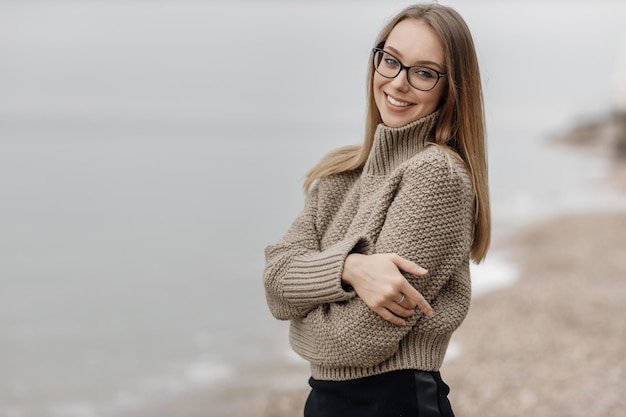 mooie jonge vrouw in gezellige kleding in de buurt van de zee