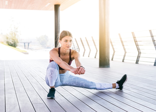 Mooie jonge vrouw in sportkleding stretching oefening doen