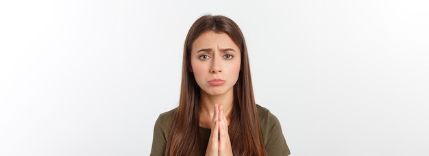 Mooie jonge vrouw in vrijetijdskleding hand in hand samen en bidden geïsoleerd op wit