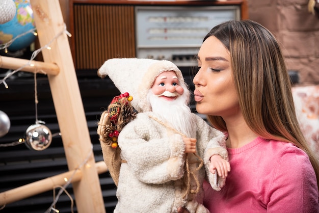 Gratis foto mooie jonge vrouw kussende pop thuis.