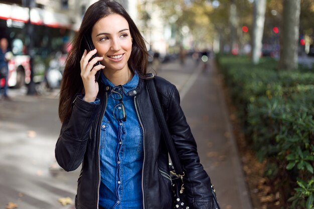 Mooie jonge vrouw met behulp van haar mobiele telefoon in de straat.