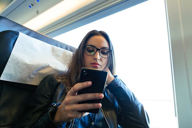 Mooie jonge vrouw met behulp van haar mobiele telefoon in de straat.