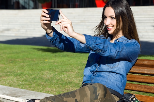 Mooie jonge vrouw met behulp van haar mobiele telefoon in de straat.