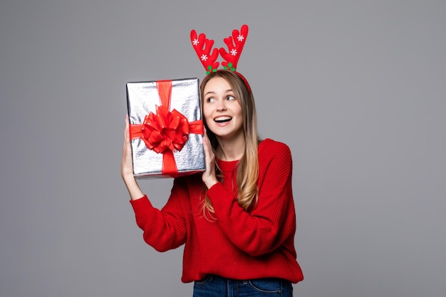 Mooie jonge vrouw met geschenkdoos slijtage in rode hoorns op grijze muur