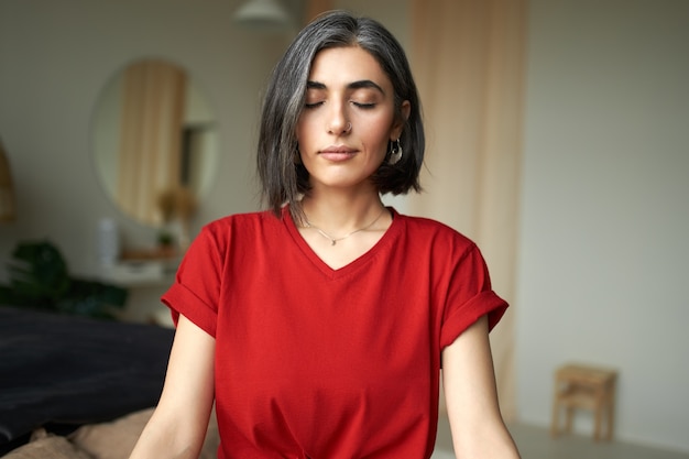 Mooie jonge vrouw met grijs haar en neusring mediteren binnenshuis, met behulp van ademhalingstechniek Gratis Foto