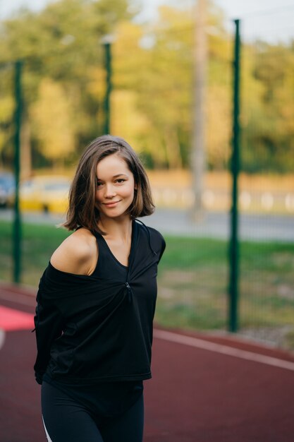 Mooie jonge vrouw op de speelplaats die de voorzijde bekijkt