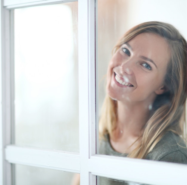 Gratis foto mooie jonge vrouw poseren achter het raam