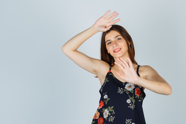 Mooie jonge vrouw poseren terwijl palmen in blouse tonen en vrolijk kijken