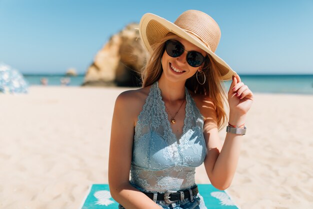 Mooie jonge vrouw zittend op het zand op het strand