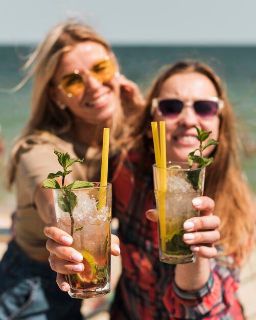 Mooie jonge vrouwen die van zomercocktails genieten