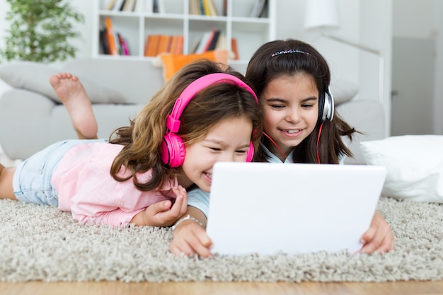 Mooie jonge zussen luisteren naar muziek met digitale tablet a