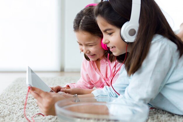 Mooie jonge zussen luisteren naar muziek met digitale tablet a