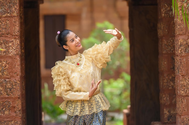 Gratis foto mooie jongedame gekleed in prachtige thaise kostuums poseren handen in thai dancing in tempel tijdens songkran festival thai new year family day in april