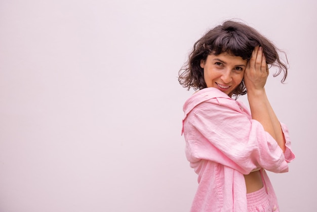 Mooie Kaukasische jonge brunette meisje in roze kleding kijkt naar camera op witte achtergrond met plaats voor tekst Lifestyle concept