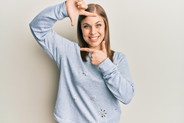 Mooie kaukasische vrouw die vrijetijdskleding draagt die glimlacht en een frame maakt met handen en vingers met een blij gezicht, creativiteit en fotografieconcept