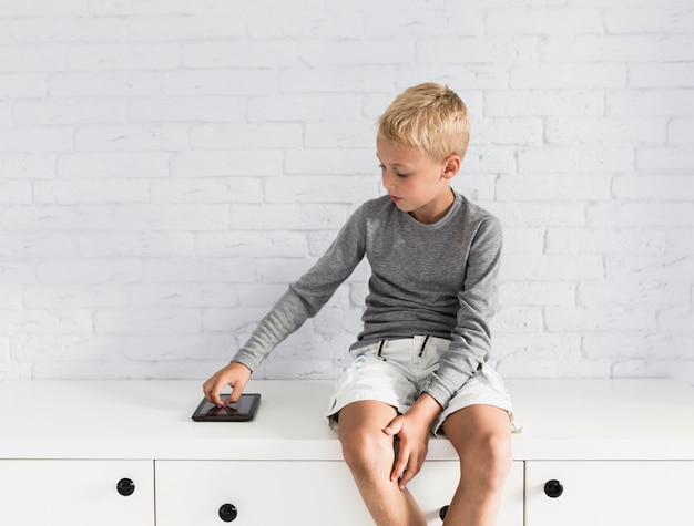 Gratis foto mooie kleine jongen met plezier met tablet