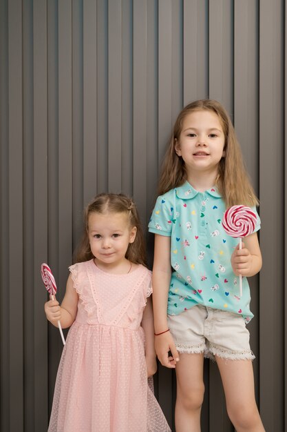 Mooie kleine meisjes met lollypop op grijze achtergrond