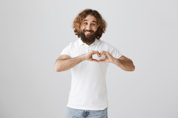 Mooie knappe man van het Midden-Oosten met hart gebaar en glimlachen