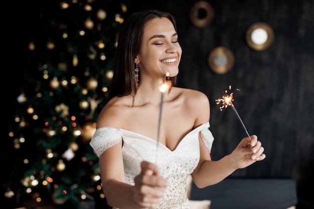 Mooie lachende vrouw in jurk met champagne en vuurwerk