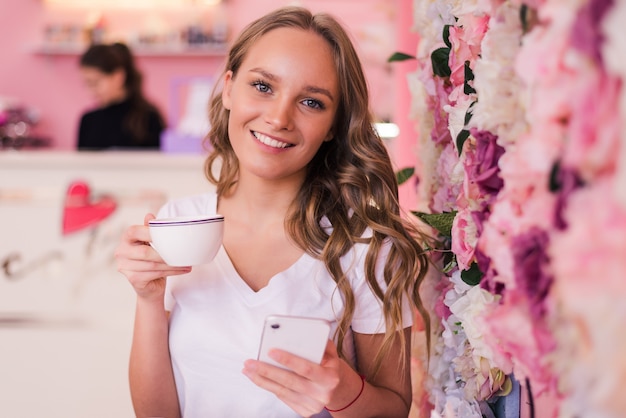 Mooie lachende vrouw koffie drinken in café. Portret van een rijpe vrouw in een cafetaria die hete thee drinkt