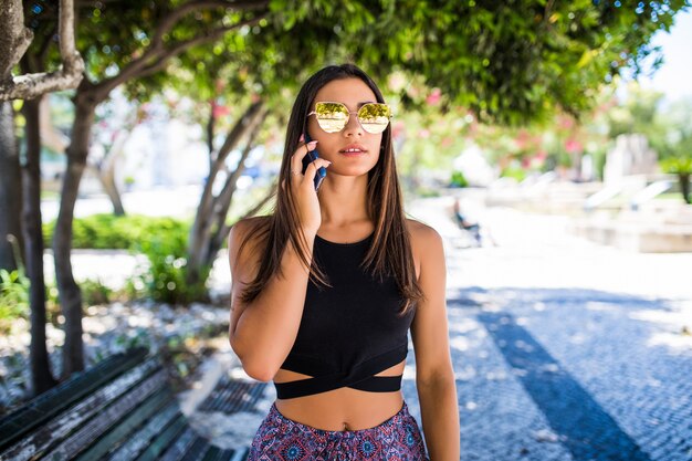 Mooie Latijns-vrouw praten aan de telefoon en lachend in een park