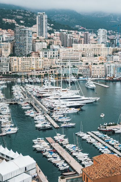 Mooie luchtfoto van een dok met veel geparkeerde schepen en een stedelijke stad op de achtergrond