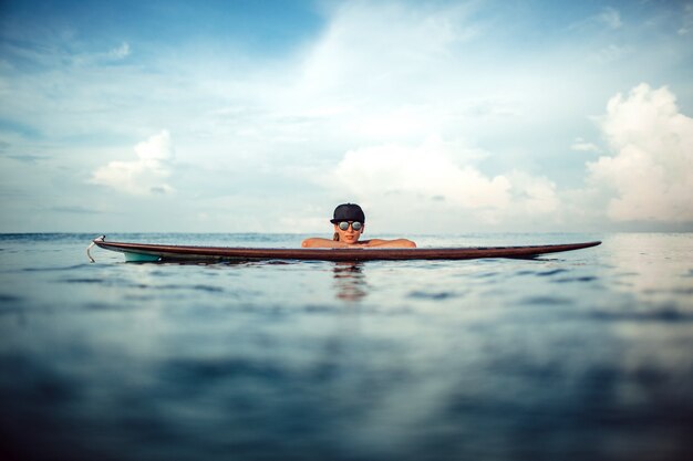 Mooie meisjes stellende zitting op een surfplank in de oceaan