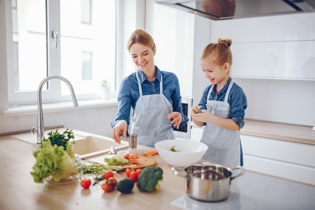 mooie moeder in een blauw shirt en schort bereidt thuis een verse groente salade