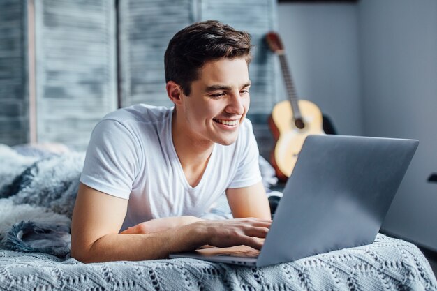 Mooie, mooie man zit op internet op zijn laptop