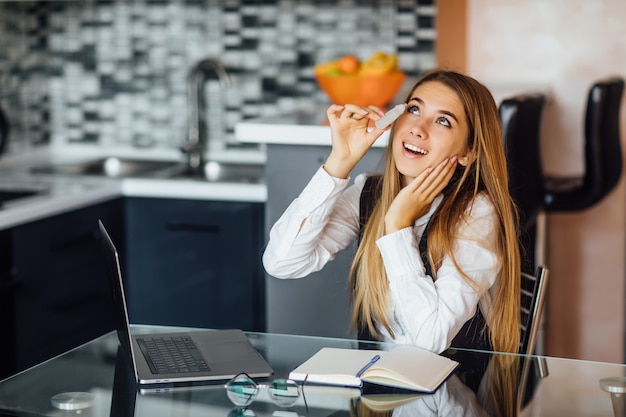 Mooie mooie vrouw gebruikt spray voor de ogen, voelt zich goed na lang laptopgebruik, zit thuis