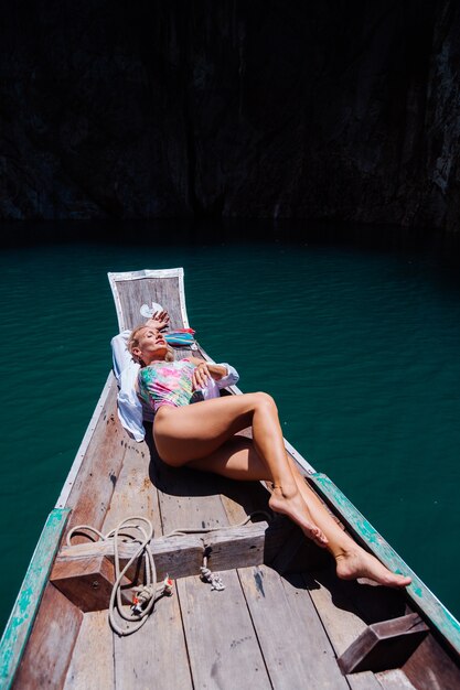 Mooie mooie vrouw in zwembroek op rand op boot