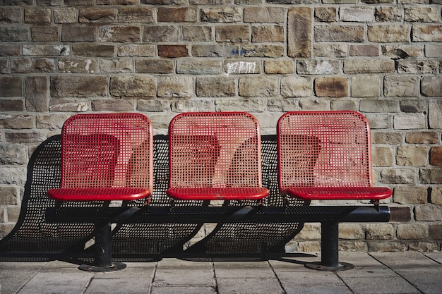 Gratis foto mooie opname van drie rode stoelen in het busstation van een stedelijk gebied