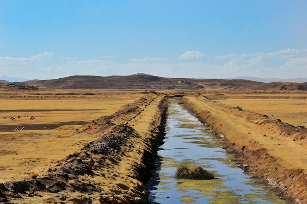 Mooie opname van een irrigatiekanaal midden in een woestijnachtig gebied met heuvels als achtergrond