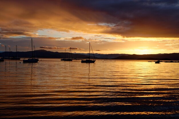 Mooie oranje getinte zonsondergang met bootsilhouetten in Santo Antonio de Lisboa, Florianopolis, Brazilië