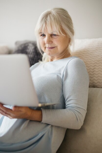 Mooie rijpe vrouw met laptop in de woonkamer