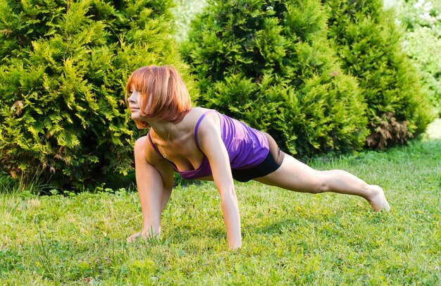 Mooie rode vrouw die fitness of yoga oefeningen doet