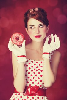 Mooie roodharige vrouwen met donut. foto in retro stijl met bokeh op de achtergrond.