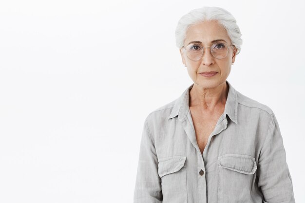 Mooie senior vrouw in glazen glimlachen, witte achtergrond