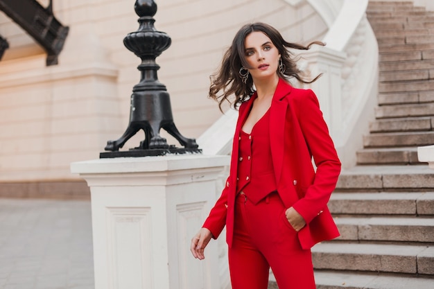 Mooie sexy rijke zakenvrouw in rood pak wandelen in de stad straat, lente zomer modetrend