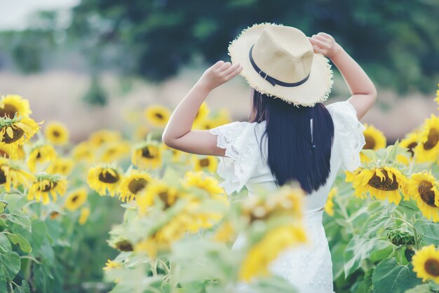 mooie sexy vrouw in een witte jurk lopen op een veld met zonnebloemen