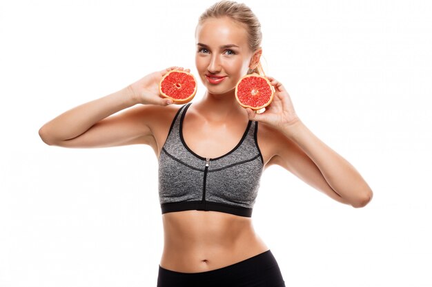 Mooie sportieve vrouw poseren, grapefruit houden